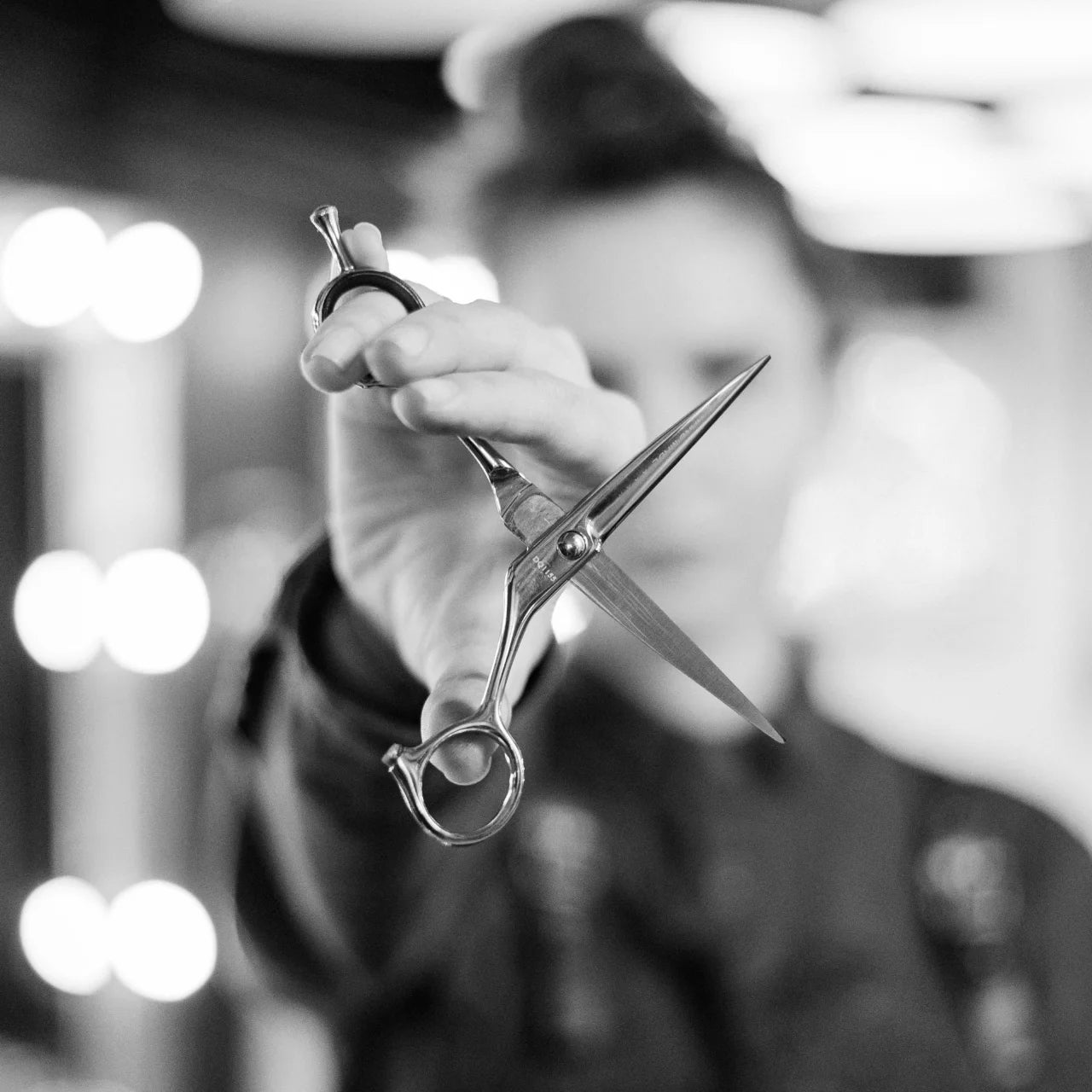 A person holding scissors sideways to show the blades and pivot point. 