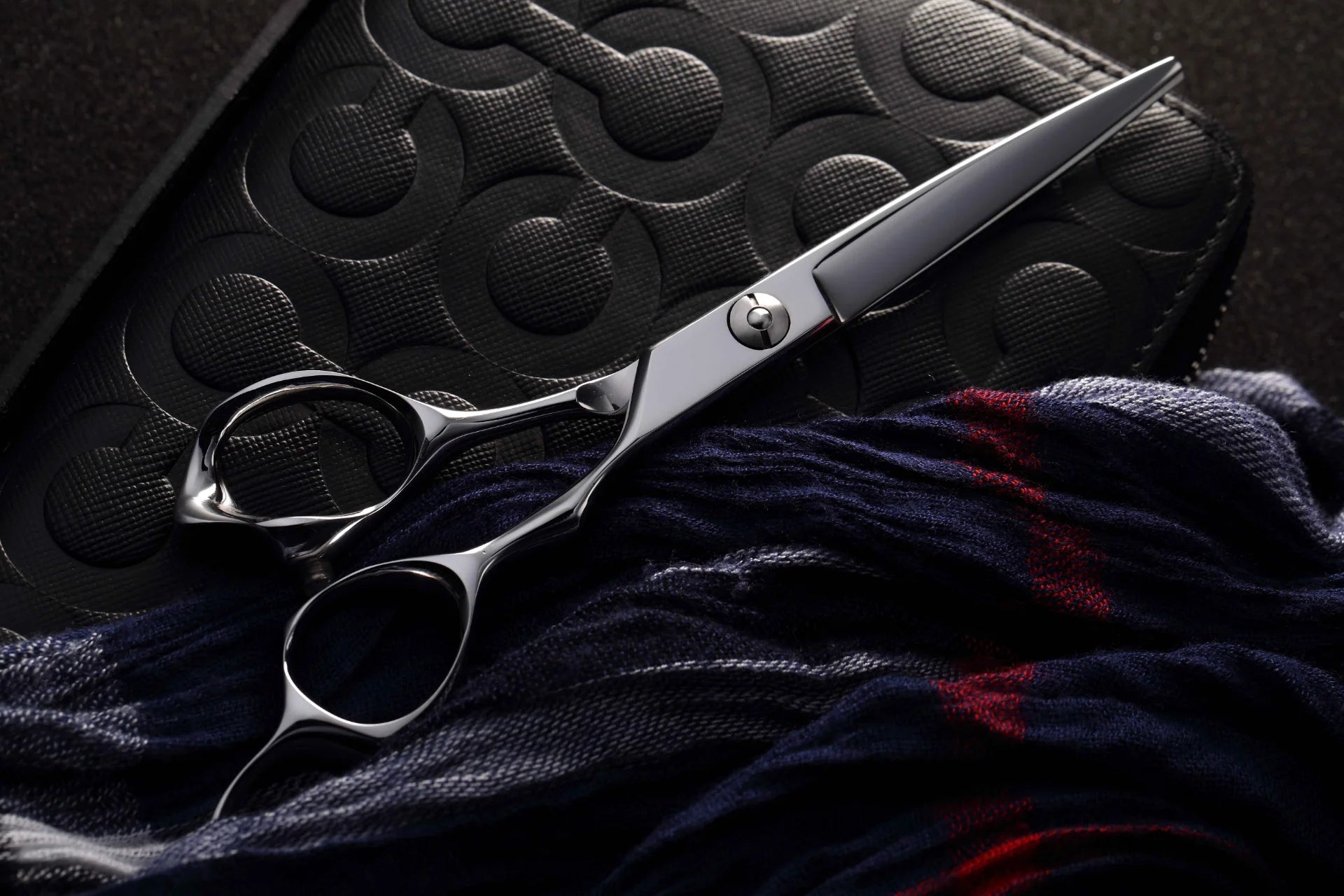A pair of shears with a leather case and blue and red scarf